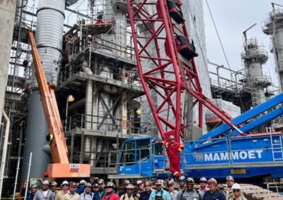 Group of workers standing in front of industrial capital project site with tall crane behind them