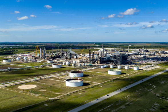 An oil refinery stands prominently in a vast field, showcasing industrial structures against a natural landscape